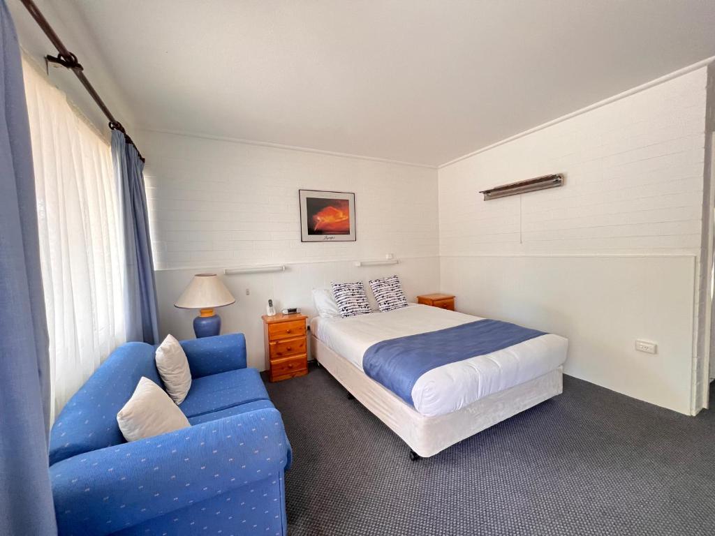 a bedroom with a bed and a blue couch at Sturt Motel Balranald in Balranald