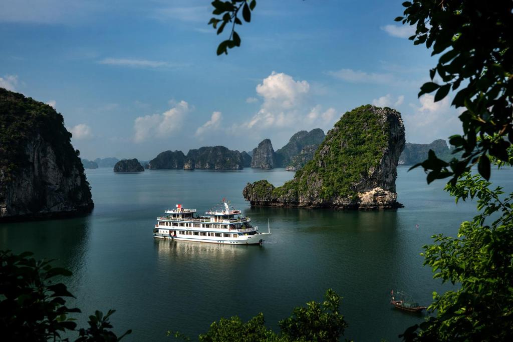 un barco en una gran masa de agua con formaciones de piedra caliza en Swan Cruises Halong en Ha Long