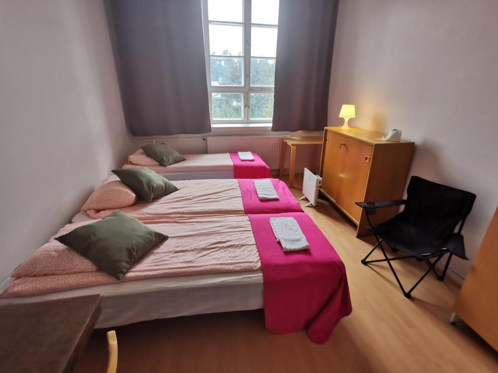 - une petite chambre avec 2 lits et une chaise dans l'établissement Kotkan Residenssi Guesthouse Huonemajoitus, à Kotka