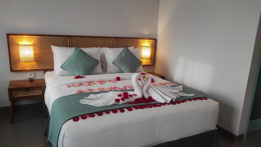 a bedroom with a large white bed with flowers on it at de'Govin Hotel in Tjakranegara