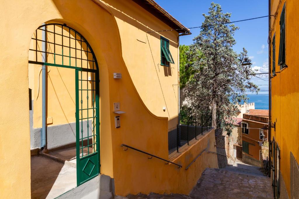 a yellow building with a green door on a street at Casa la Fortezza in Porto Santo Stefano