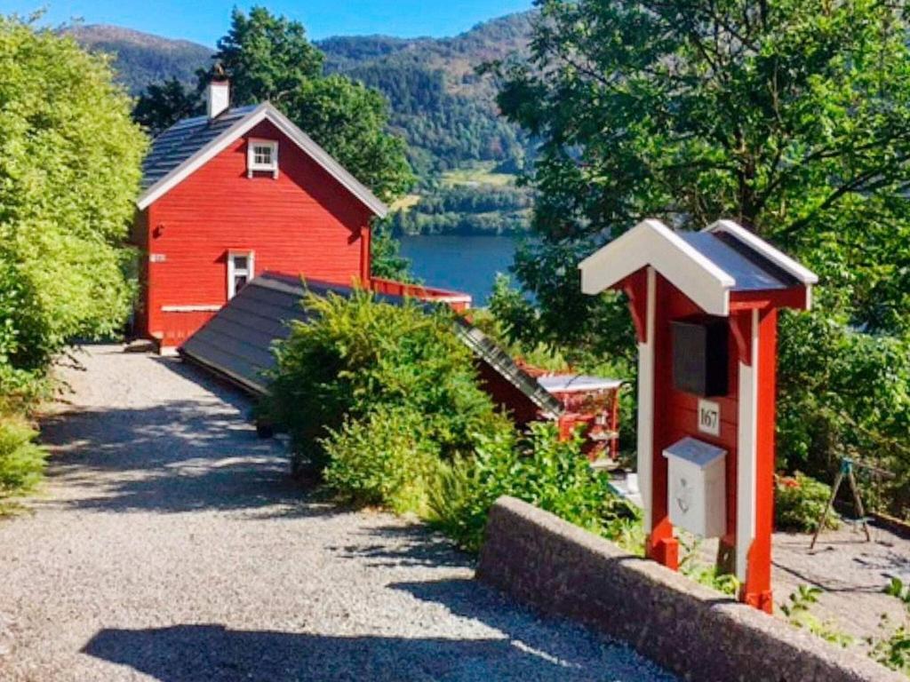 a red barn with a small house next to a lake at Holiday home Bruvik in Bruvik