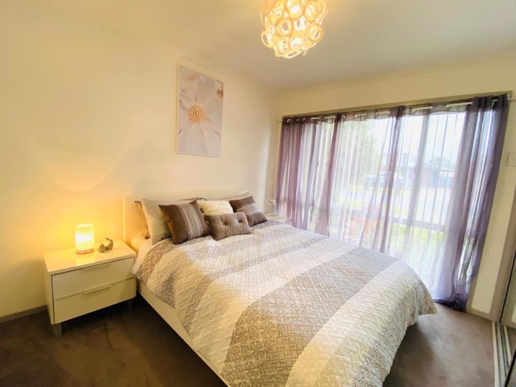 a bedroom with a bed and a window with a chandelier at ENTIRE HOME IN WERRIBEE,BEST POSSIBLE LOCATION YOU CAN FIND in Werribee