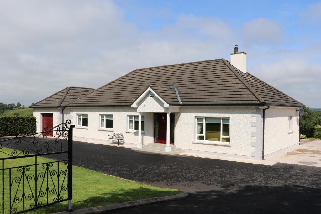 a white house with a black roof at Laneside Haven - 5 Minutes from Castleblayney - Accessible, Gated with Patio, Garden and Gym! in Monaghan