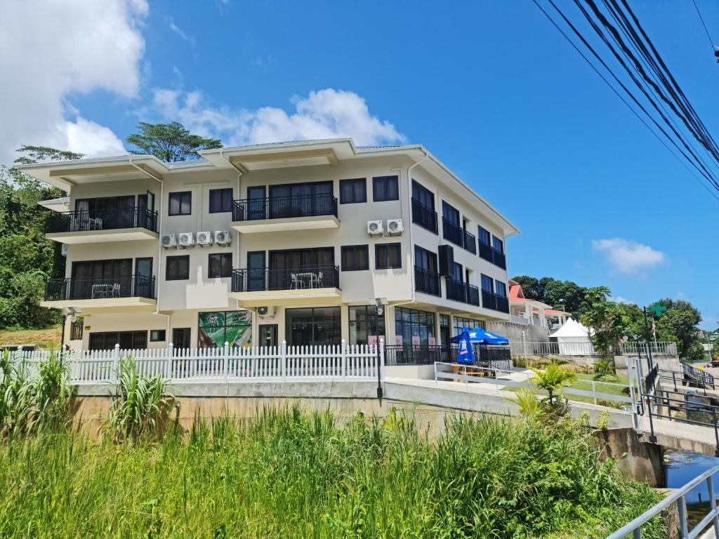 a white building with balconies on a beach at B Holiday Apartments in Beau Vallon