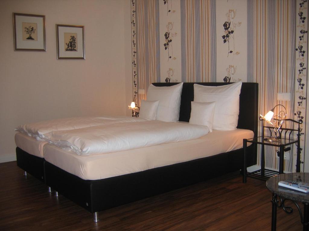 1 cama con sábanas blancas y almohadas en una habitación en Gästehaus Oswald en Forst