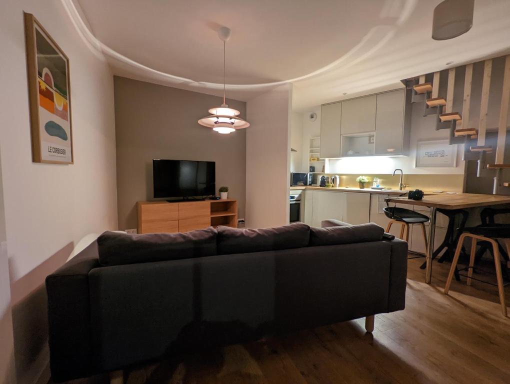 a living room with a couch and a kitchen at Le 5 bis, une maison de ville dans le centre historique in Saint-Galmier