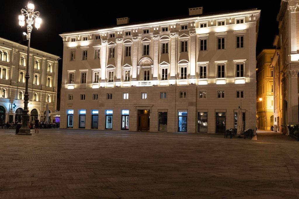 un grande edificio bianco di notte con un lampione di Grand Hotel Duchi d'Aosta Apartments a Trieste