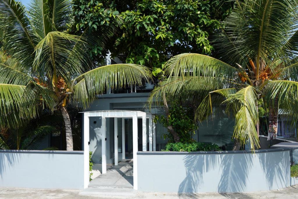 una casa blanca con palmeras delante en MOONSHELL RESIDENCE en Baa Atoll