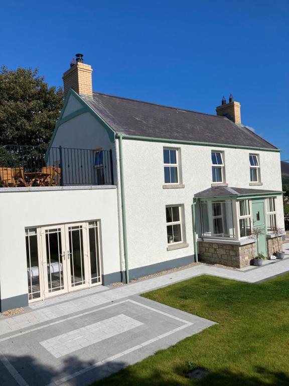 ein großes weißes Haus mit Rasen davor in der Unterkunft Sage Gables Mourne Mountains in Annalong