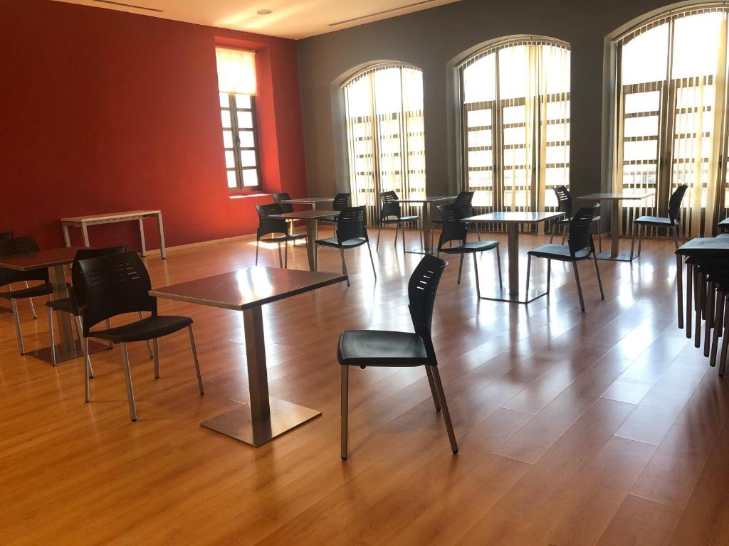 Una gran sala con mesas, sillas y ventanas. en Tres Estrellas Camí de Sirga Mequinenza, en Mequinenza