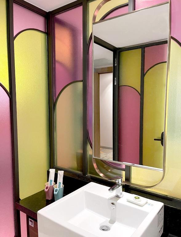a bathroom with a sink and two mirrors at OLAH Poshtel - Taichung Station in Taichung