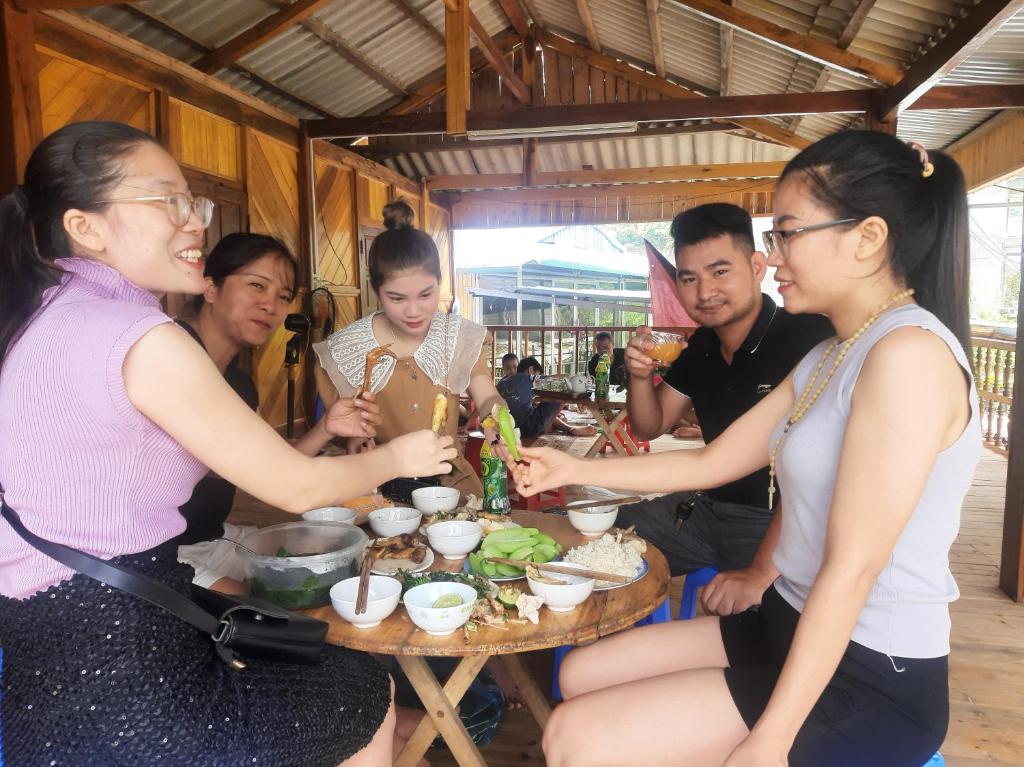 Un groupe de personnes assises autour d'une table et mangeant de la nourriture dans l'établissement Má Si H'MÔNG HOMESTAY Tả Phìn, à Sa Pa
