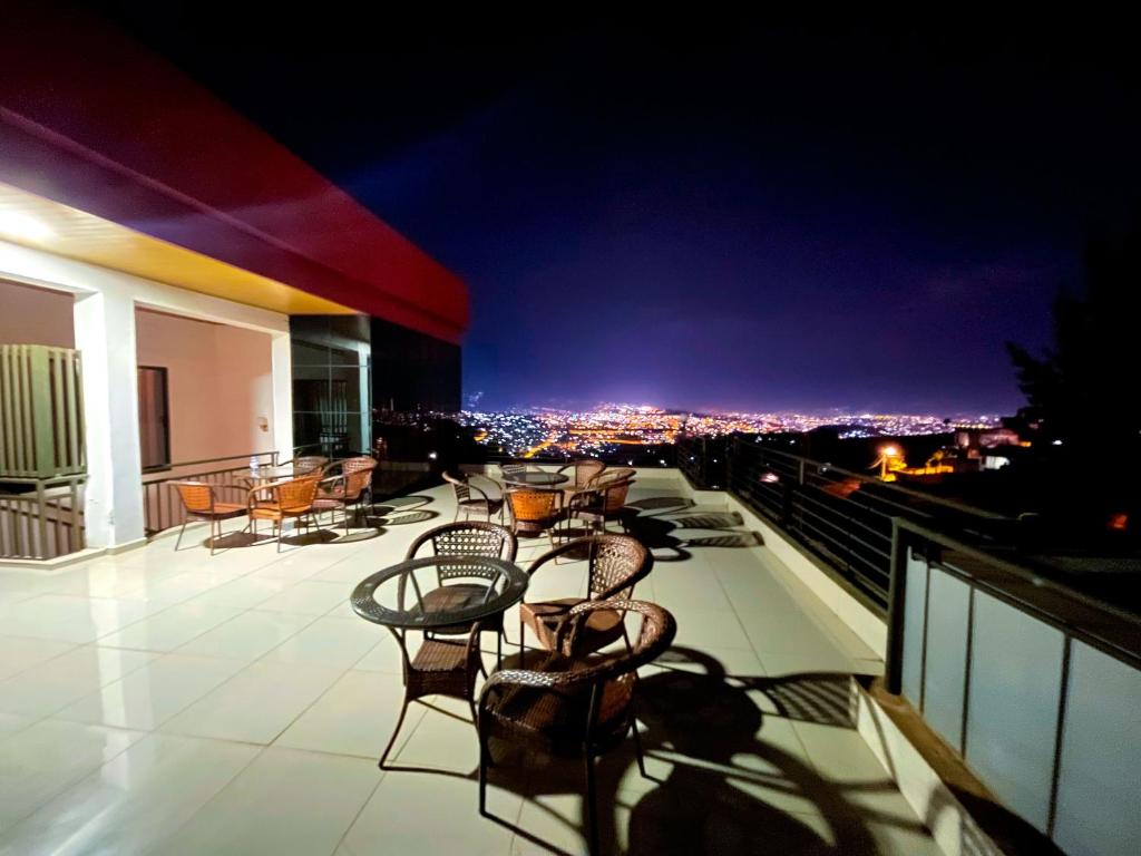 een dakterras met stoelen en 's avonds tafels bij Rebero View Apartments in Kigali