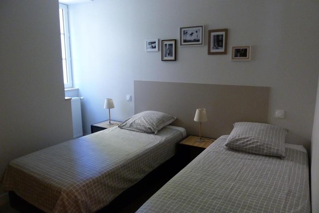 two beds in a bedroom with two lamps and pictures on the wall at Chez Berni in Millau