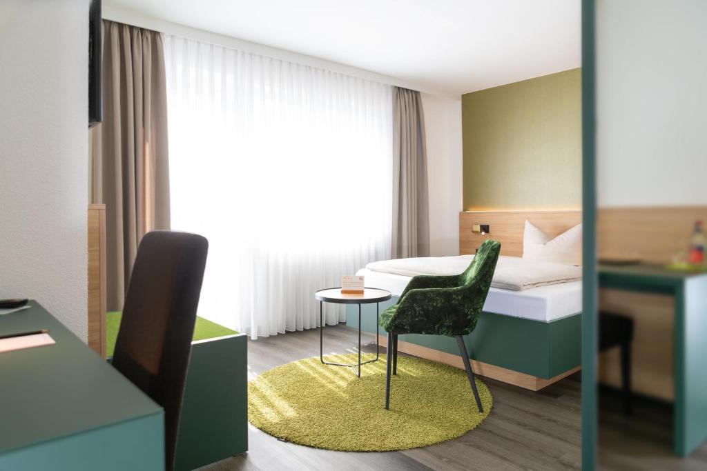 - une chambre avec un lit, une chaise et une table dans l'établissement Hotel-Restaurant Bierhäusle, à Fribourg-en-Brisgau