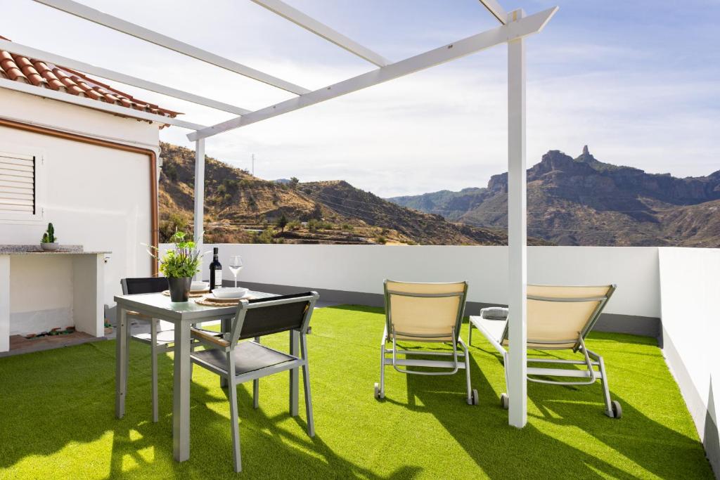 a patio with a table and chairs on the grass at Casa Isabela with Roque Nublo view in Tejeda