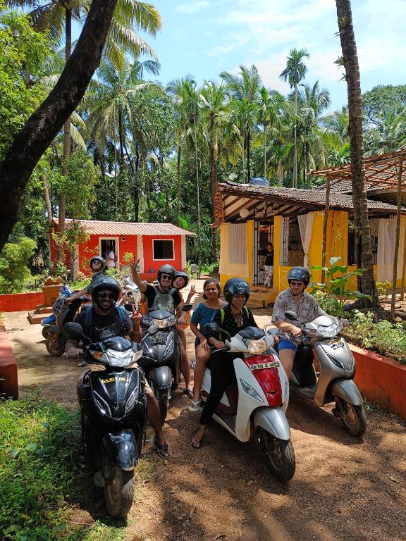 a group of people riding scooters on a dirt road at BunkNBrew in Palolem