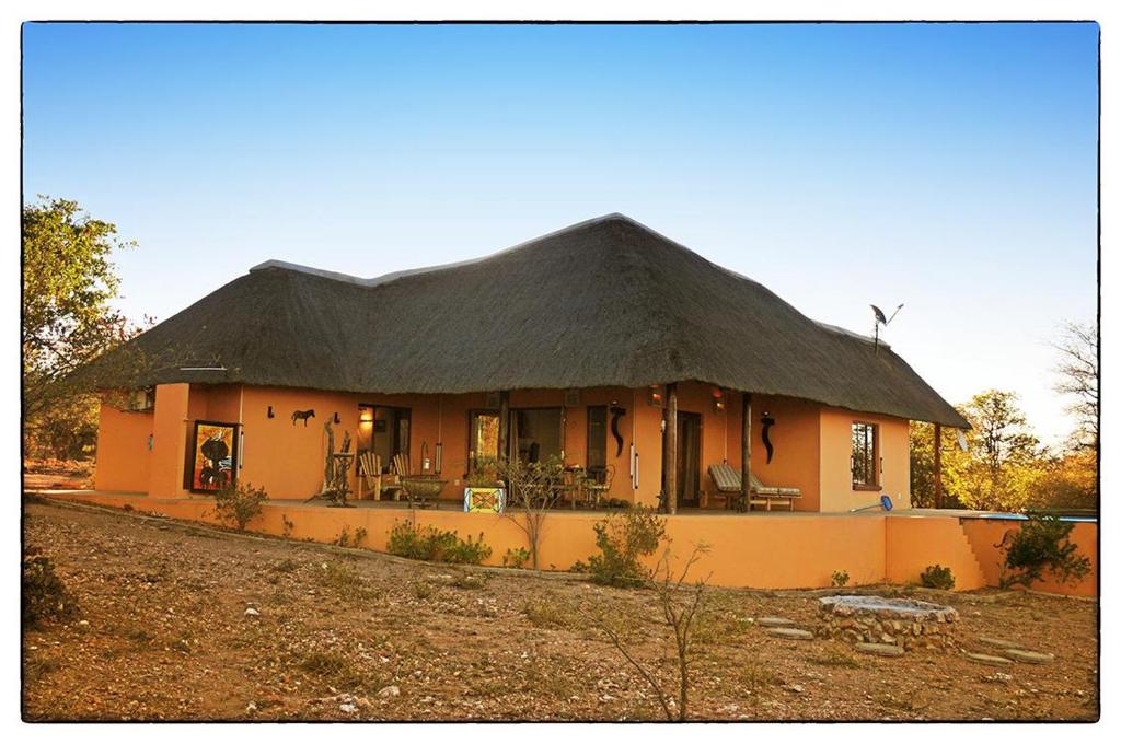 a large house with a thatched roof at Game Lodge bordering Kruger with splash pool in Phalaborwa