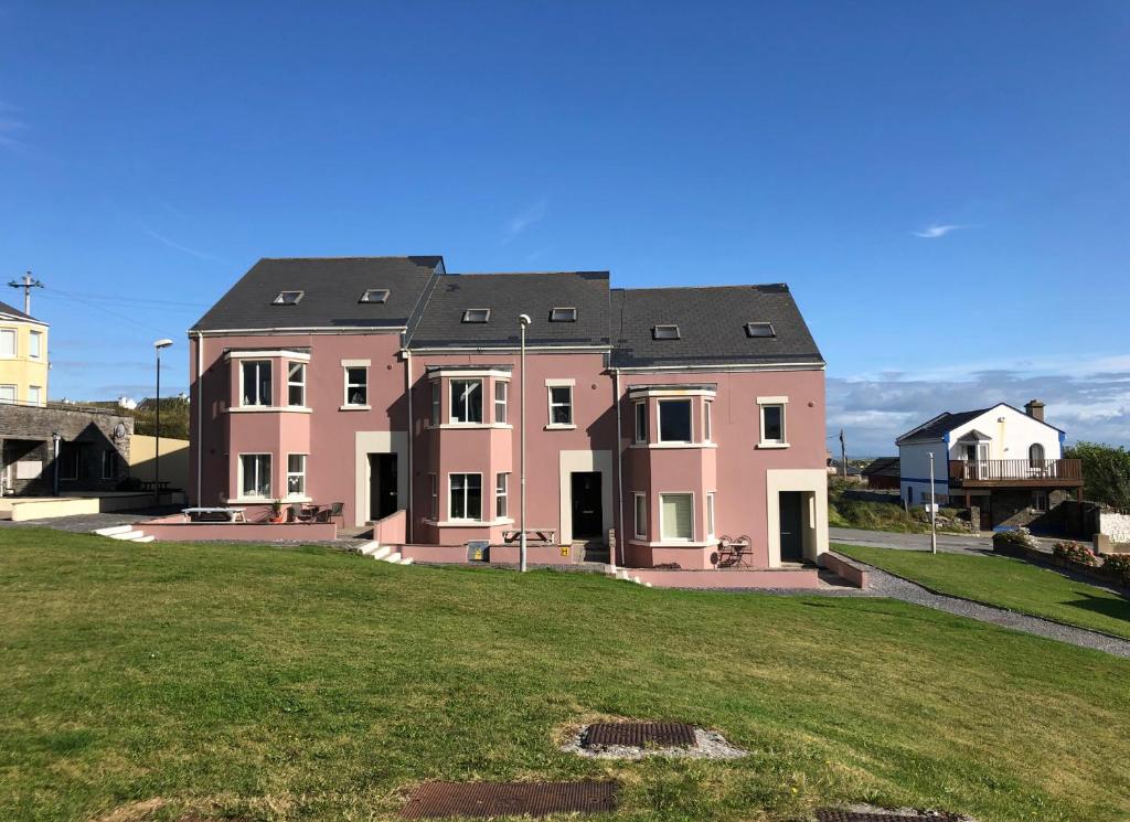 a large pink house on a grassy field at Spanish Cove Holiday Homes (Sleeps 5) in Kilkee