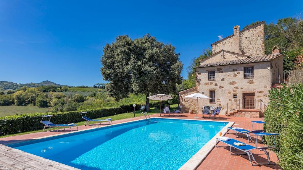 une piscine en face d'une maison avec des chaises et d'un bâtiment dans l'établissement LE GRAZIE 8, Emma Villas, à Montepulciano