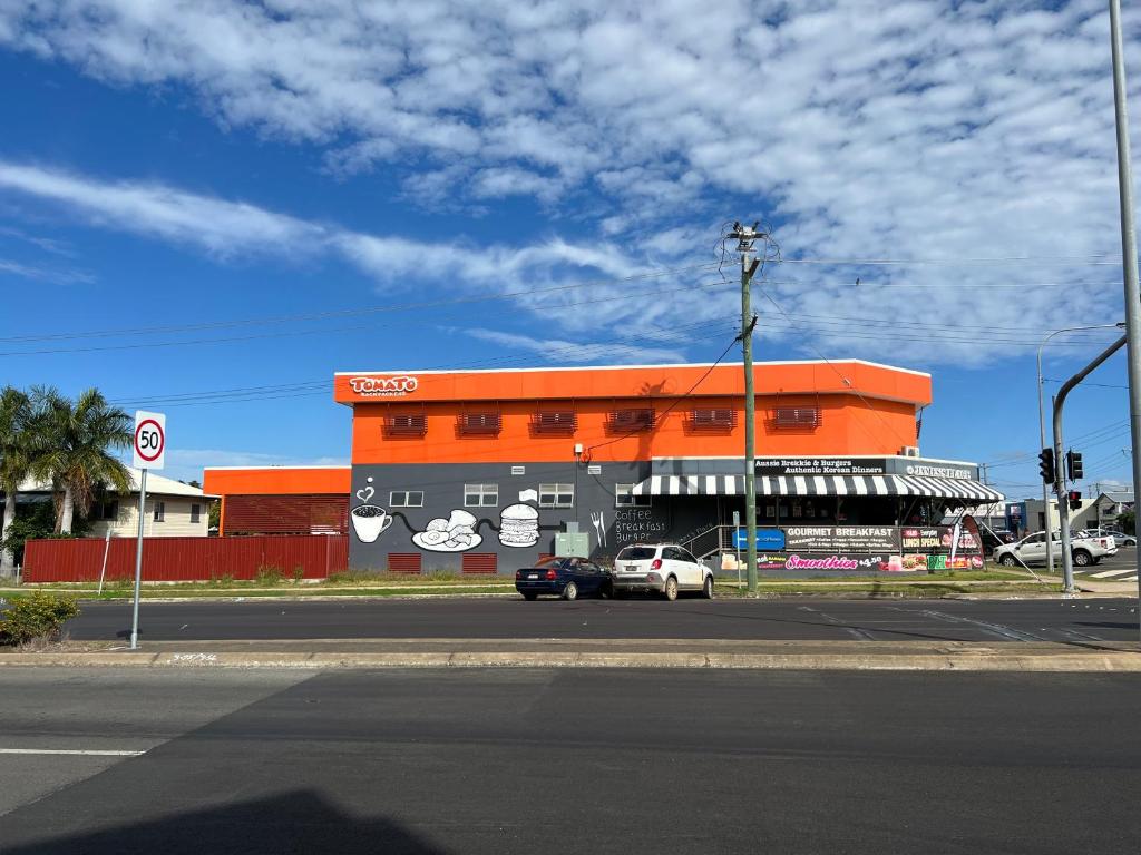 an orange building with a car parked in front of it at Tomato Backpackers in Bundaberg