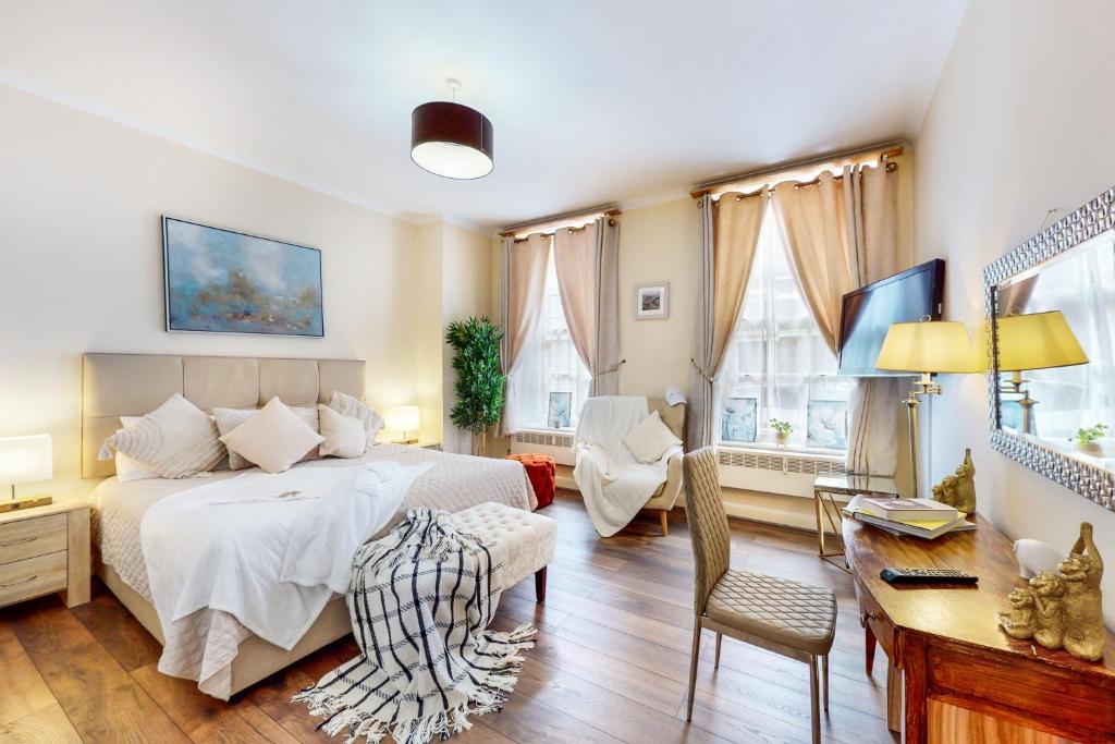 een slaapkamer met een bed, een bureau en stoelen bij Park Lane Apartments/Shaw House in Londen