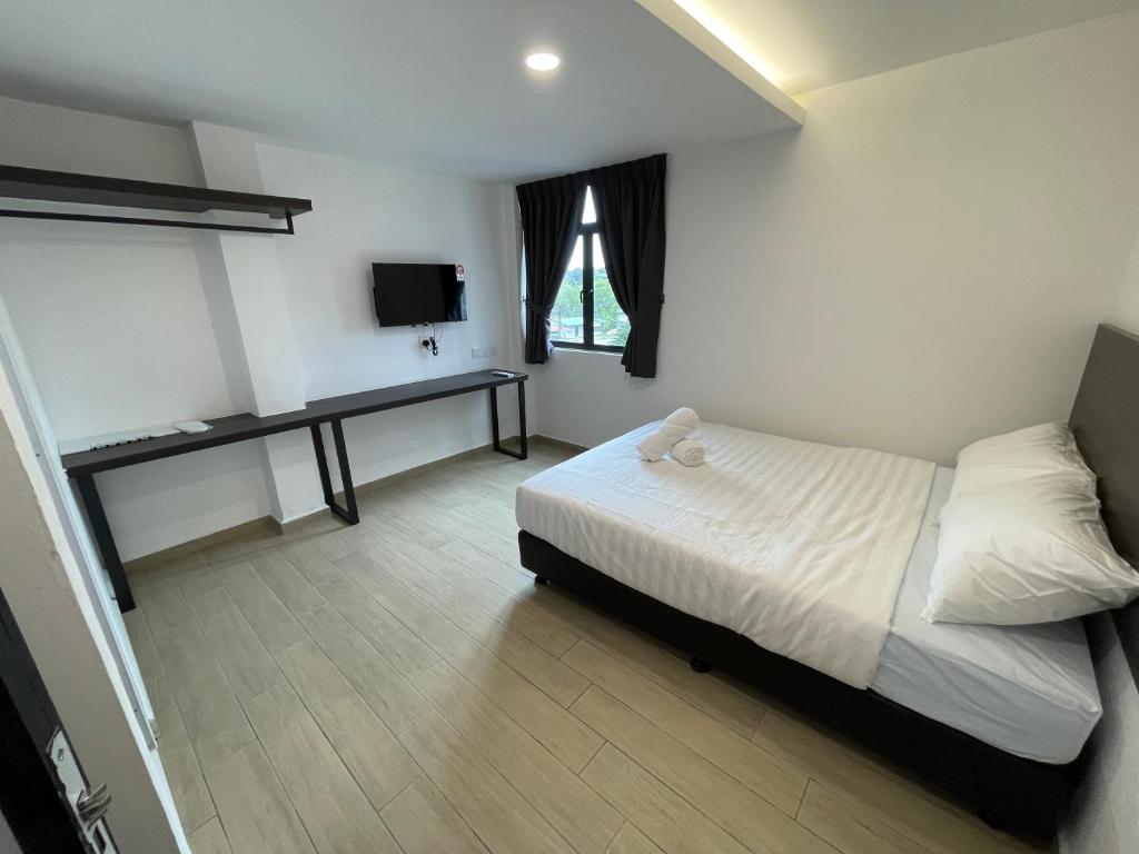 a bedroom with a bed and a desk and a television at E Hotel in Kulim