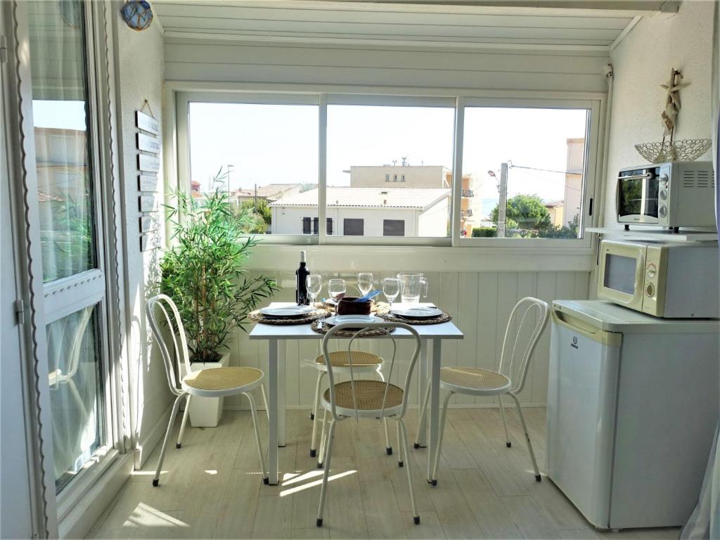 eine kleine Küche mit einem Tisch und Stühlen sowie einem Fenster in der Unterkunft Apartment Les Balcons de la Méditerranée-15 by Interhome in Narbonne-Plage