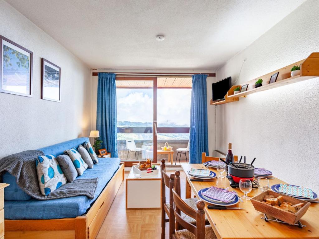 uma sala de estar com uma mesa e um sofá azul em Apartment Lunik Orion-18 by Interhome em Le Corbier