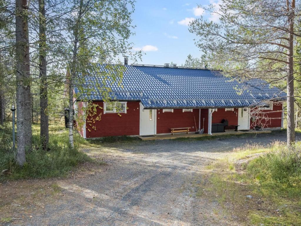 a red house with a blue roof in the woods at Holiday Home Rintelä 5a by Interhome in Ruka