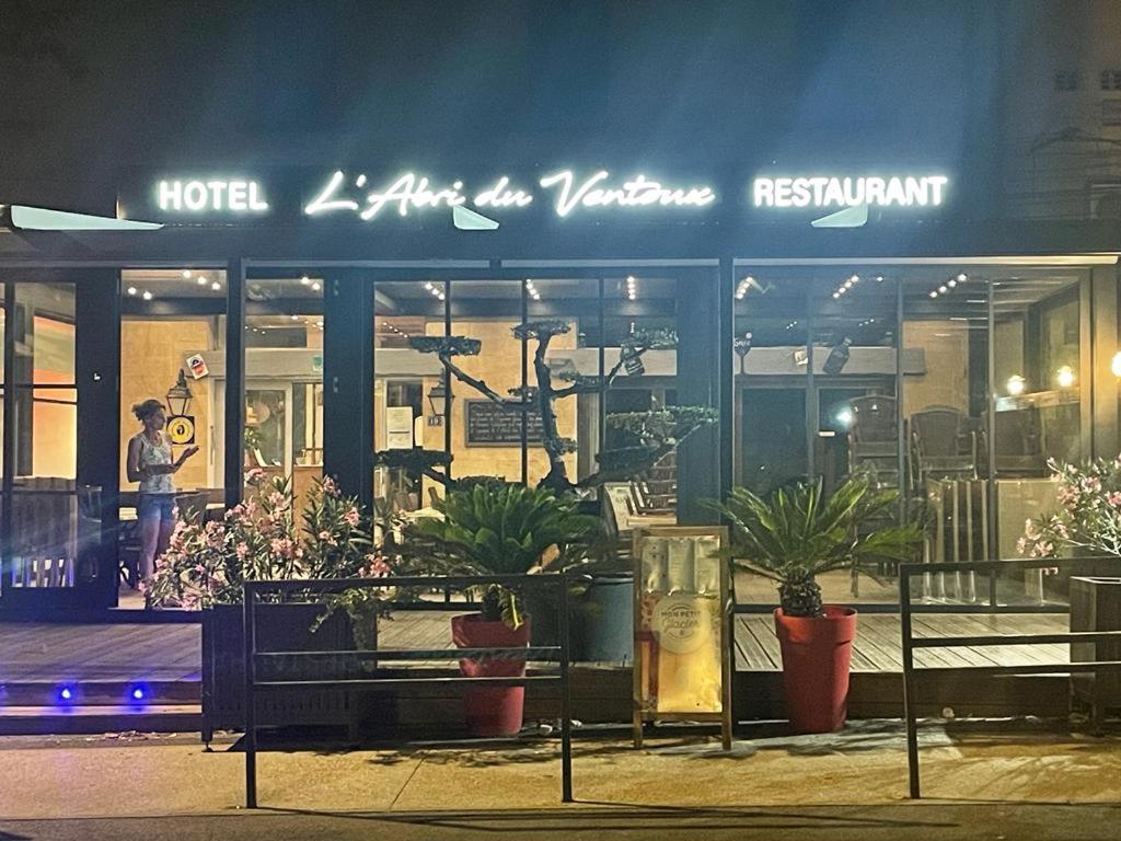a person standing outside of a hotel at night at Abri Du Ventoux in Malaucène