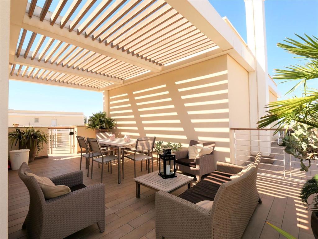 patio z drewnianą pergolą, stołem i krzesłami w obiekcie Apartment La Marina by Interhome w mieście Dogana
