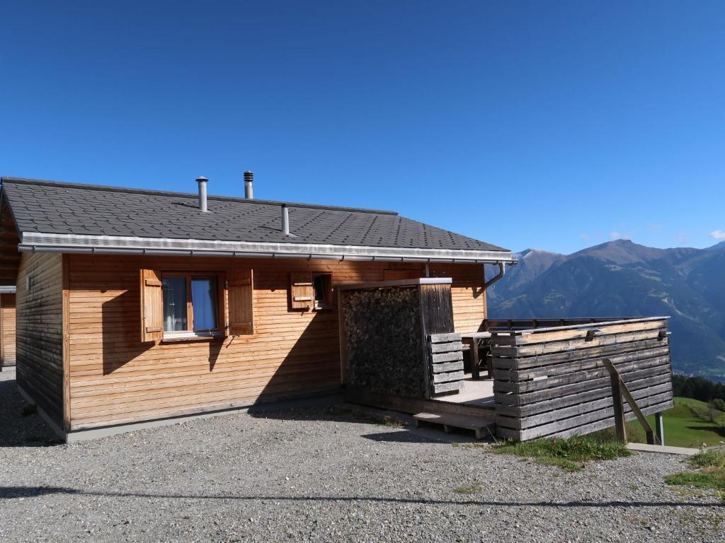 a wooden cabin with mountains in the background at Holiday Home Superior Aclas Maiensäss Resort-1 by Interhome in Urmein