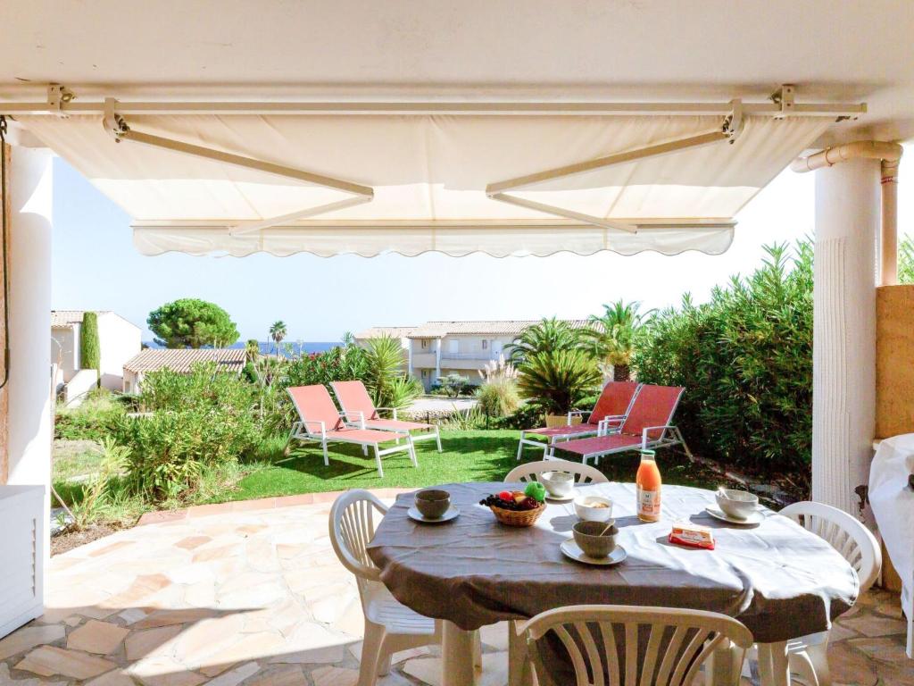 een patio met een tafel en stoelen en een parasol bij Apartment Les Mas de la Mer-2 by Interhome in Saint-Aygulf