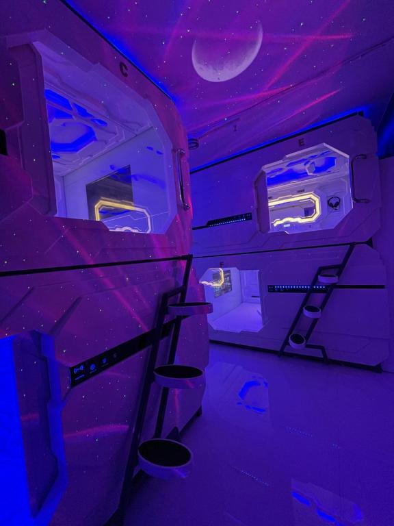 a room with purple lights and stairs in an airplane at BMAX SPACEPODS in Pusok