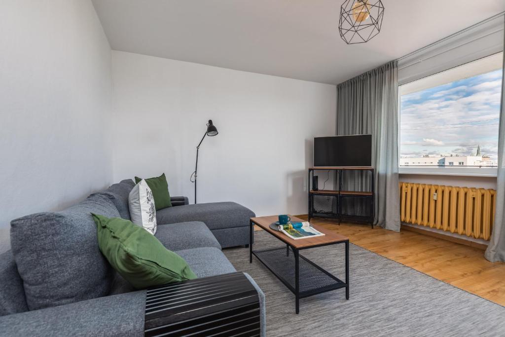 a living room with a gray couch and a tv at Salt Island Apartment Sea and Harbor View by Renters in Kołobrzeg