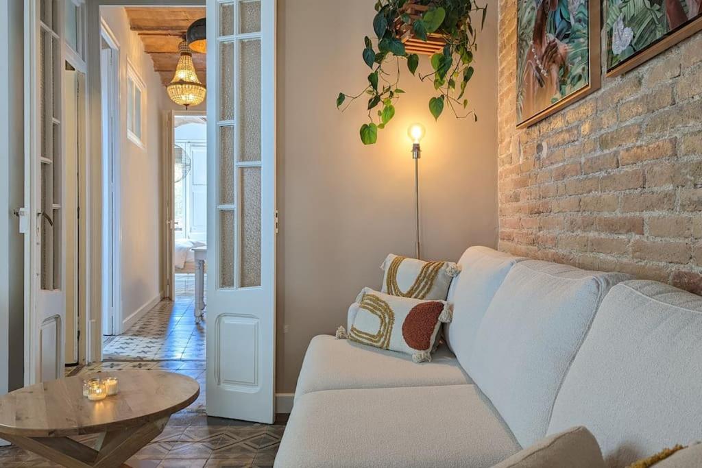 sala de estar con sofá y pared de ladrillo en CRASH'NSTAY - Casa Barna, en Barcelona