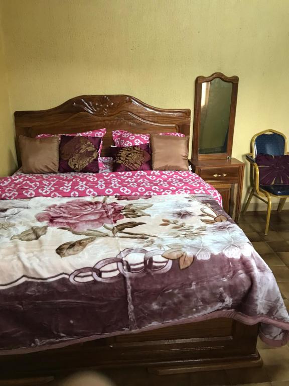 una camera con un grande letto con testiera in legno di Bel Appartement meublé à Bafoussam a Bafoussam