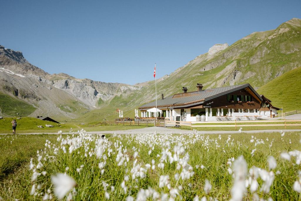ein Gebäude in den Bergen mit einem Blumenfeld in der Unterkunft Berg- & Naturhotel Engstligenalp in Adelboden