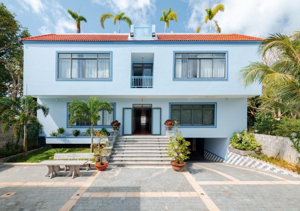 a white house with palm trees in front of it at Coco Homestay in Phú Quốc