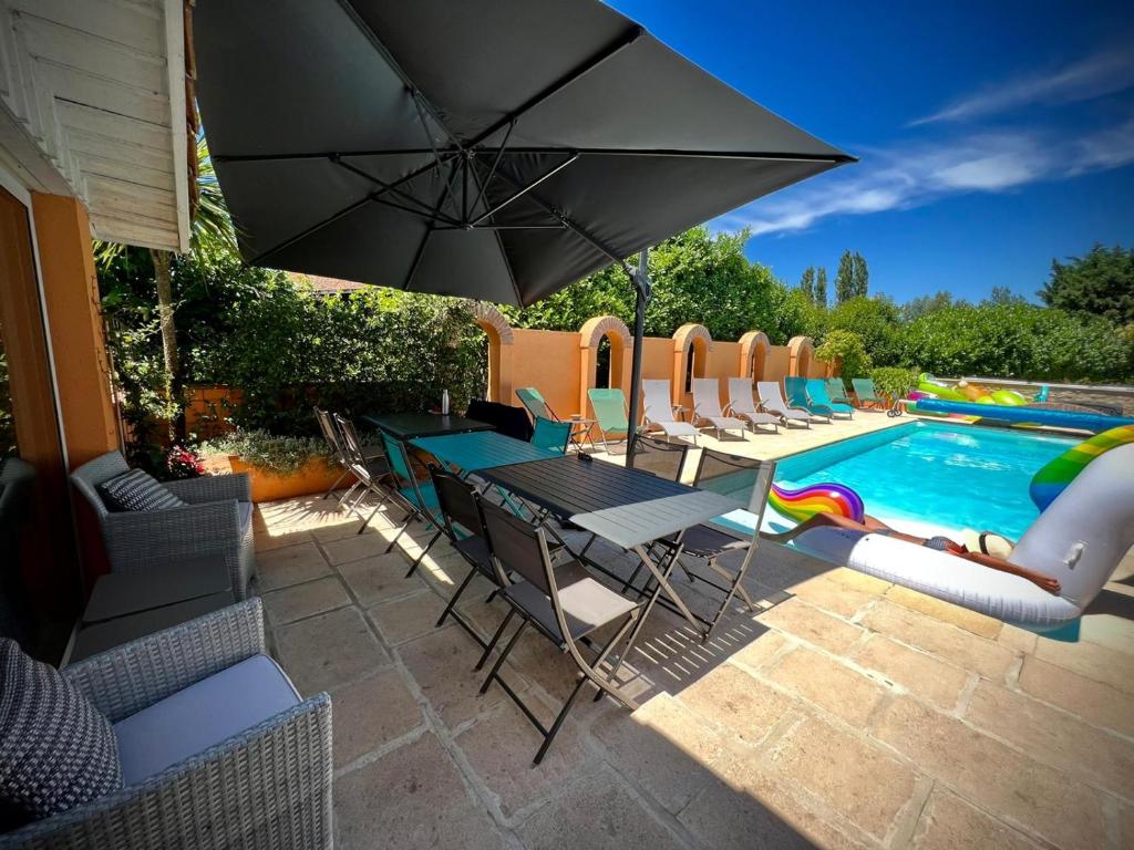 a patio with a table and chairs and a swimming pool at Domaine Des Deux Rivières in Meilhan-sur-Garonne