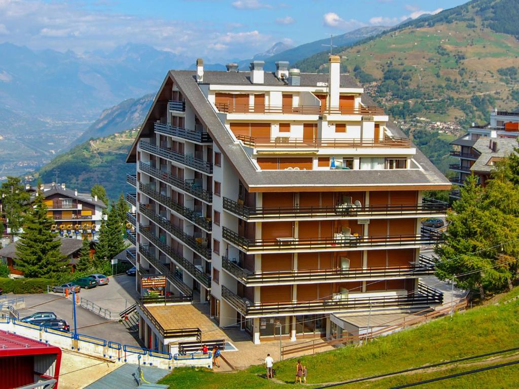 un bâtiment sur une colline avec des montagnes en arrière-plan dans l'établissement Apartment Olympic F8 by Interhome, à Nendaz