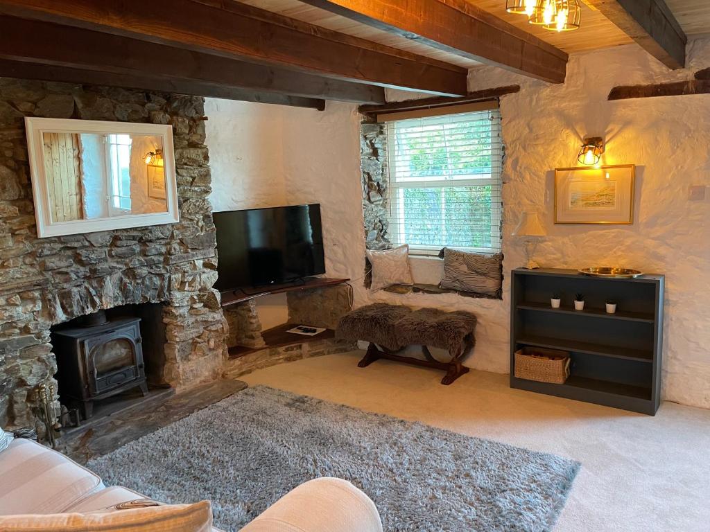 a living room with a stone fireplace and a television at Buttercup Cottage, located in the gateway to Eden! in Saint Blazey