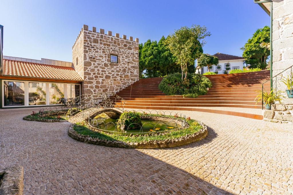 a stone building with a fountain in the middle of a courtyard at ICH Inveja Country House in Paços de Ferreira