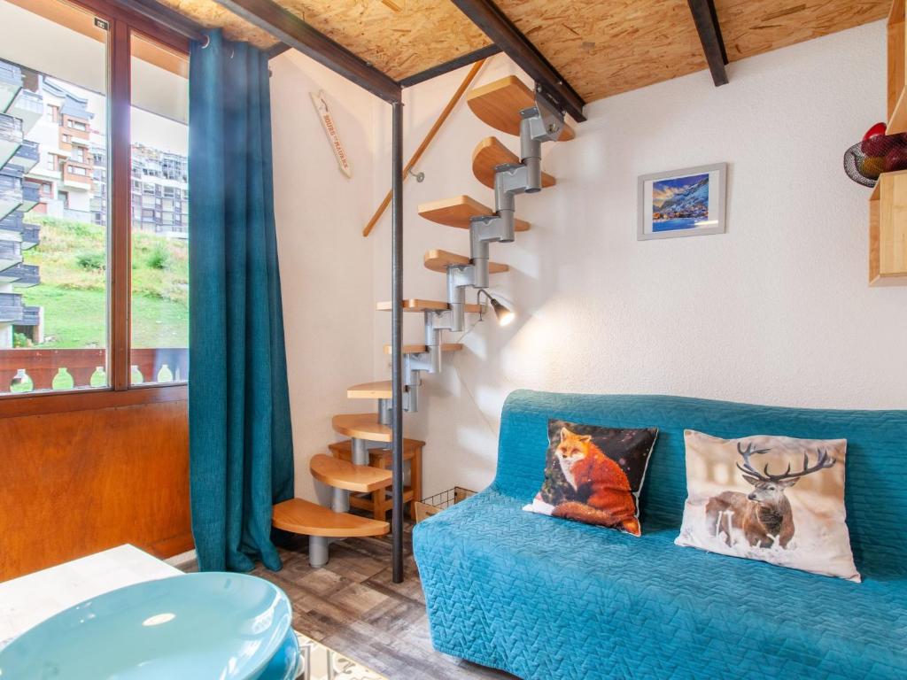 a living room with a blue couch and a spiral staircase at Studio Rond Point des Pistes-19 by Interhome in Tignes
