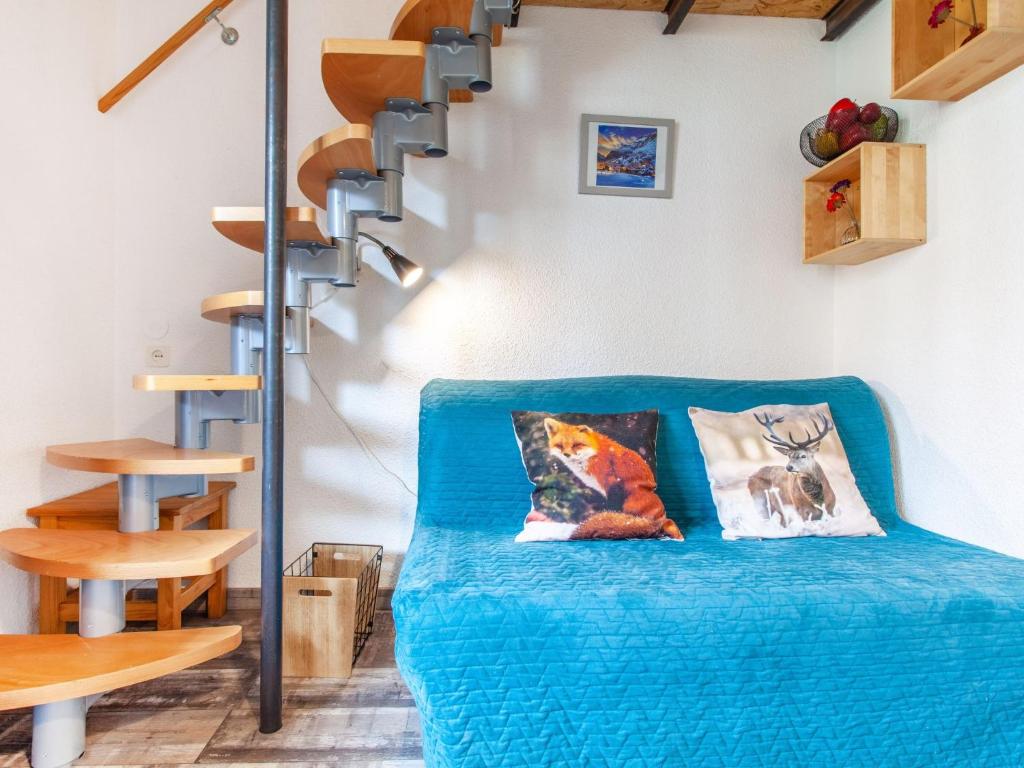 a room with a blue couch and a spiral staircase at Studio Rond Point des Pistes-19 by Interhome in Tignes