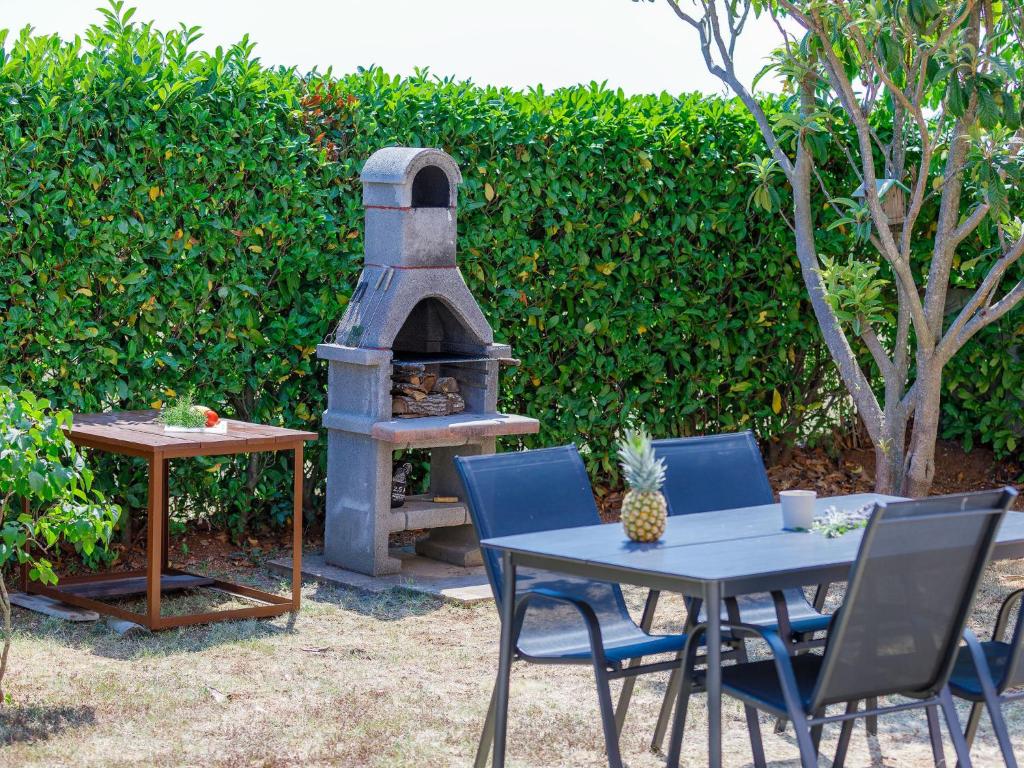 einen Tisch und Stühle mit einem Pizzaofen im Hof in der Unterkunft Holiday Home Goga by Interhome in Nedeščina