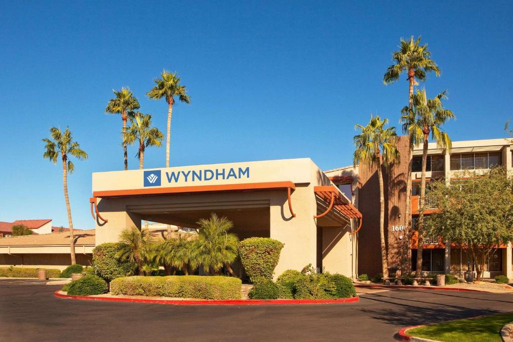 a building with palm trees and a sign for a hotel at Wyndham Phoenix Airport - Tempe in Tempe