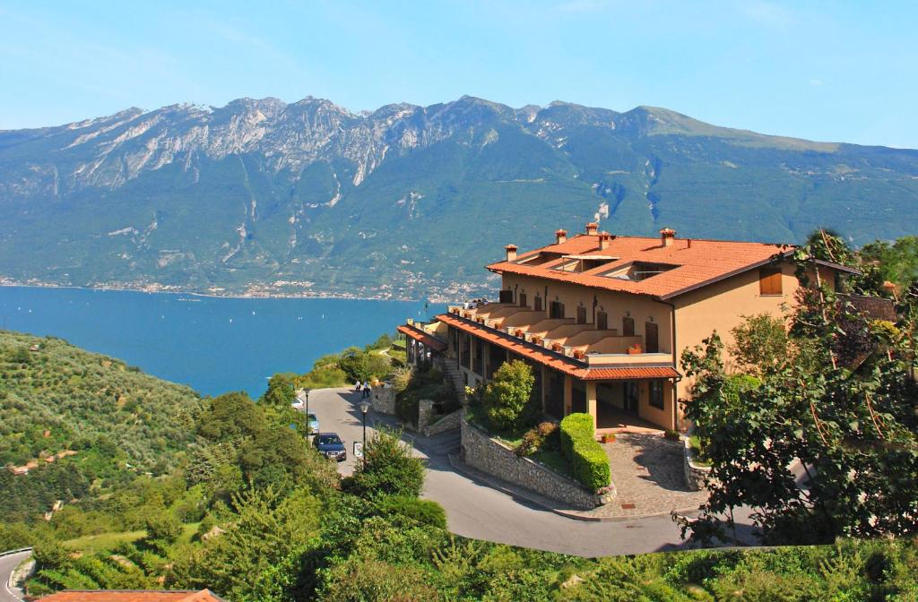 a house on a hill with a view of the water and mountains at Hotel Garnì Al Poggio in Tignale